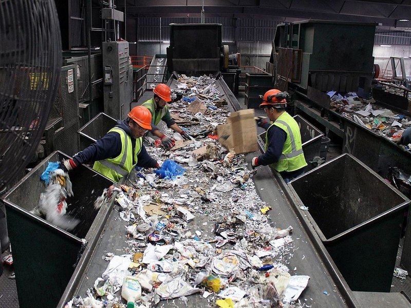 Workers sorting out recyclables from trash on a conveyor belt